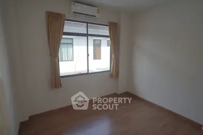 Spacious empty room with wooden flooring and large window, perfect for customization.
