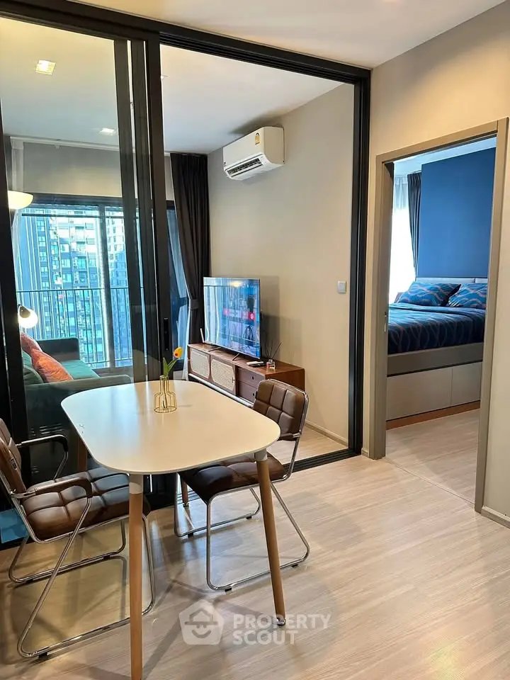 Modern apartment interior with dining area and view into bedroom, featuring sleek furniture and natural light.