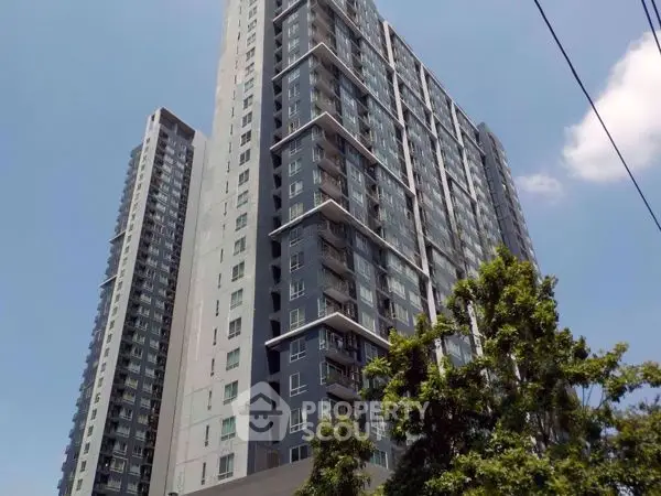 Modern high-rise building with glass facade and balconies under clear blue sky.