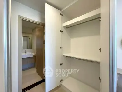 Spacious modern closet with open doors next to a sleek bathroom