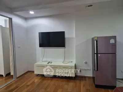 Modern living room with wall-mounted TV and sleek refrigerator, featuring wooden flooring and minimalist decor.
