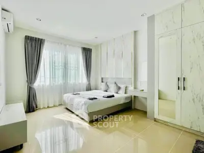 Modern bedroom with elegant decor and natural light, featuring a stylish bed and mirrored wardrobe.