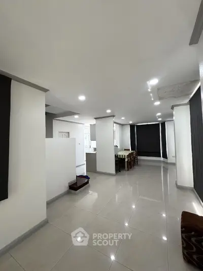 Spacious modern living area with sleek tile flooring and contemporary design.