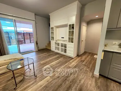 Spacious living room with modern flooring and built-in storage, opening to a large balcony.