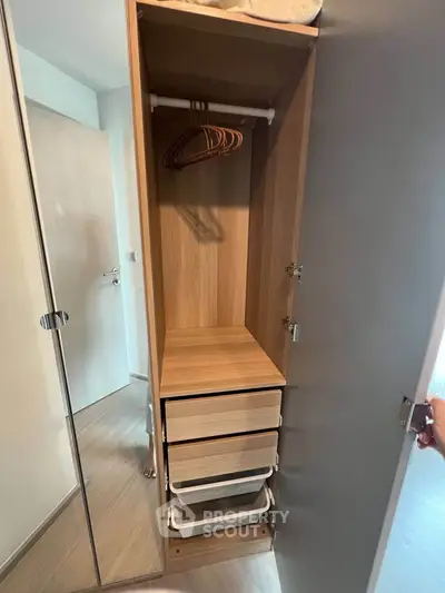 Spacious wooden wardrobe with mirror door and drawers in modern apartment