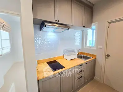 Modern kitchen with wooden countertops and sleek cabinetry in a bright apartment.