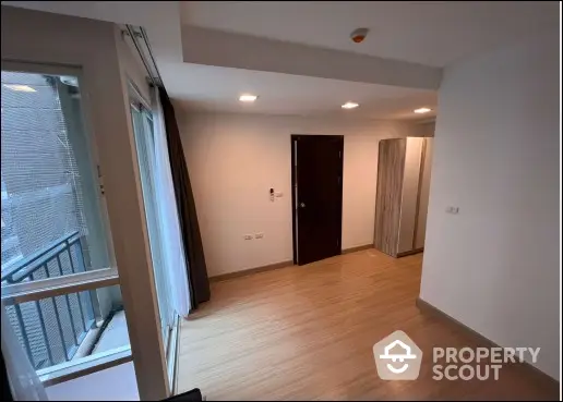 Spacious empty room with wooden flooring and large window balcony access