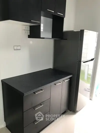 Modern kitchen with sleek black cabinets and stainless steel fridge