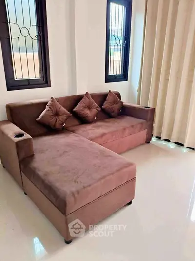 Cozy living room with plush brown sectional sofa and natural light from windows.