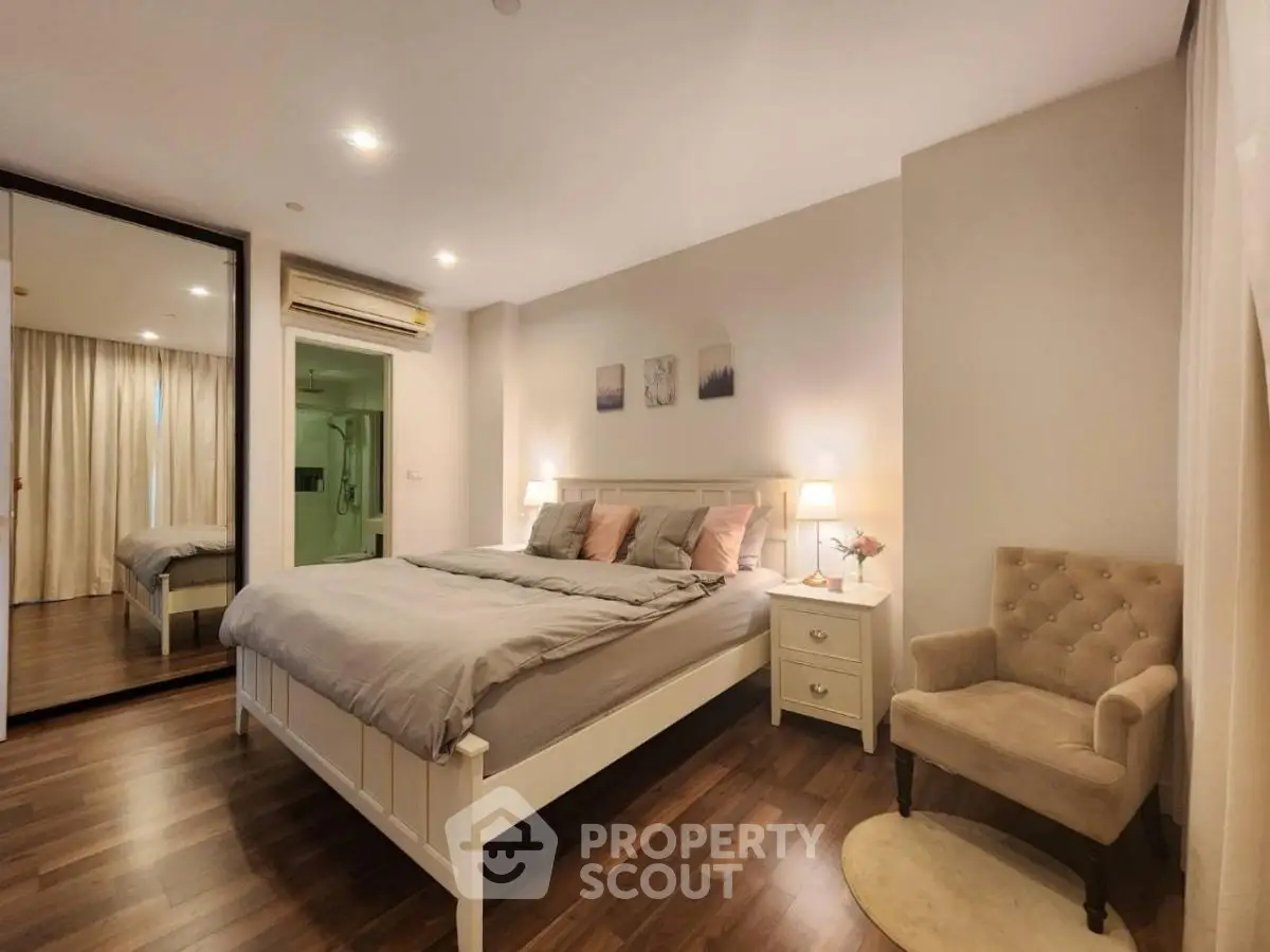 Elegant bedroom with cozy decor and soft lighting, featuring a comfortable bed and stylish armchair.
