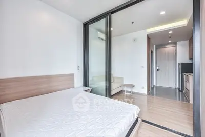 Modern bedroom with sliding glass doors leading to a cozy living area in a stylish apartment.