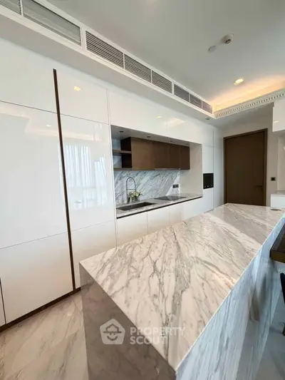 Luxurious modern kitchen with marble island and sleek cabinetry in high-end apartment.