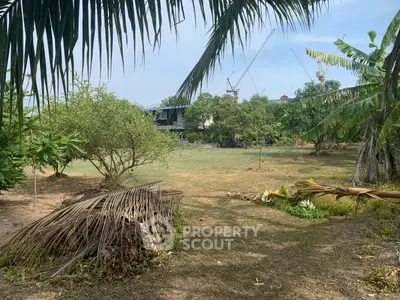 Spacious land plot with lush greenery and construction cranes in the background.