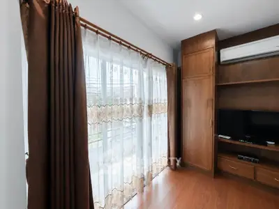 Spacious living room with elegant curtains and built-in wooden entertainment unit.