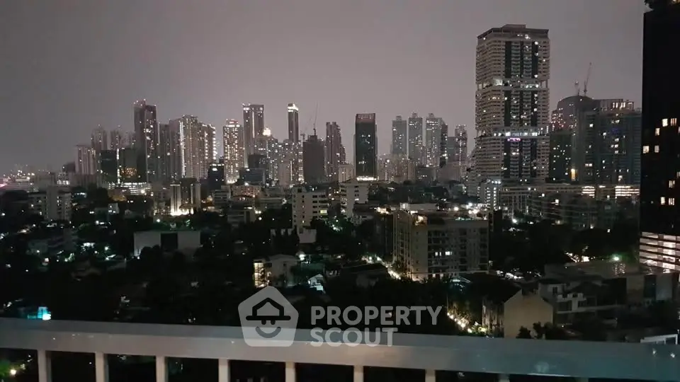 Stunning city skyline view from a high-rise balcony at night, showcasing vibrant urban living.