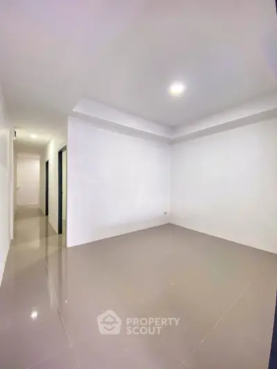 Spacious empty room with glossy tiled floor and bright lighting, ideal for customization.