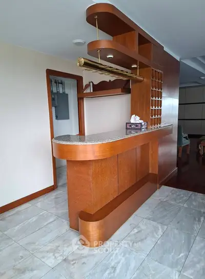 Stylish home bar with wooden finish and marble flooring in a modern living space.
