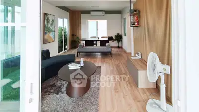 Spacious modern living room with stylish decor and wooden flooring, featuring a cozy seating area and natural light.