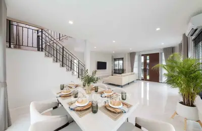 Spacious modern living room with elegant dining area and staircase, featuring bright natural light and stylish decor.