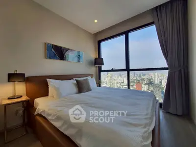Luxurious bedroom with stunning city view from large windows, featuring elegant decor and cozy bedding.