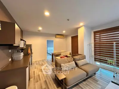 Modern open-plan living room with stylish kitchen and cozy seating area, featuring contemporary decor and ample natural light.
