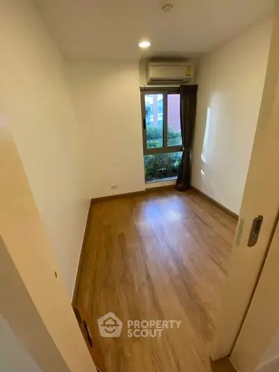 Cozy empty bedroom with wooden flooring and large window view