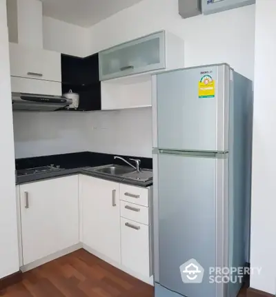 Modern compact kitchen with sleek cabinets and stainless steel fridge