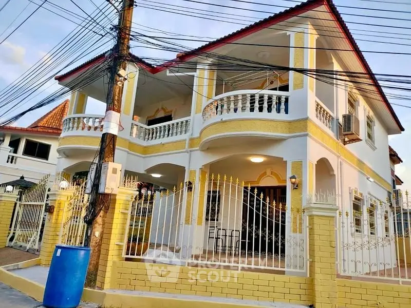Charming two-story house with elegant balcony and gated entrance in a serene neighborhood.