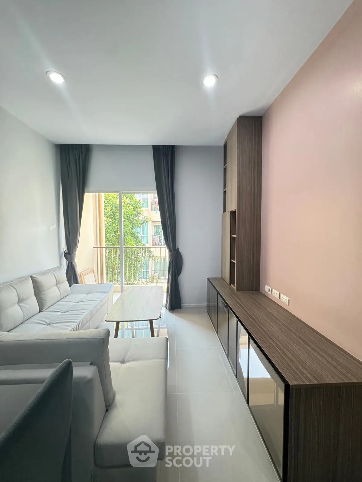 Modern living room with sleek furniture and large window offering natural light and balcony view.