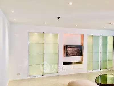 Modern living room with sleek built-in TV unit and sliding glass doors.
