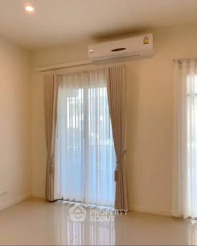 Bright and airy room with large windows and air conditioning, perfect for comfortable living.