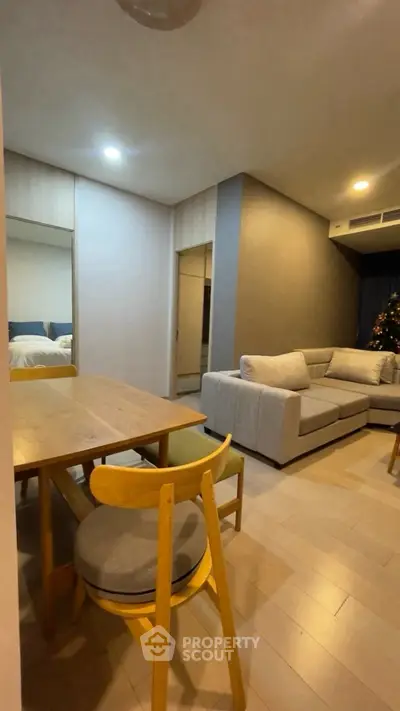 Modern living room with cozy sectional sofa and dining area in open layout apartment.