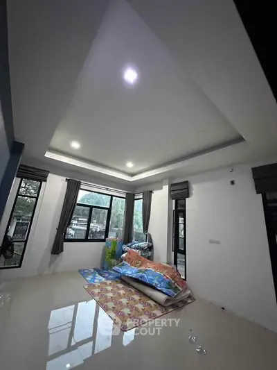 Spacious living room with large windows and modern ceiling design, perfect for natural light.
