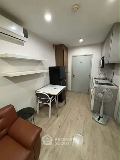 Modern compact living room with kitchen, featuring sleek design and efficient use of space.