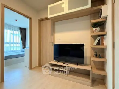 Modern living room with sleek TV unit and open shelving, leading to a cozy bedroom with natural light.