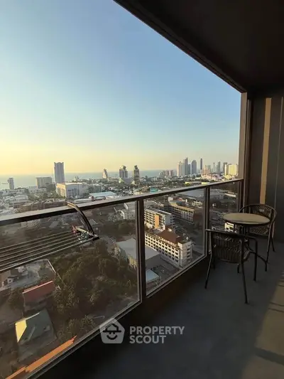 Stunning high-rise balcony with panoramic city and ocean views at sunset.