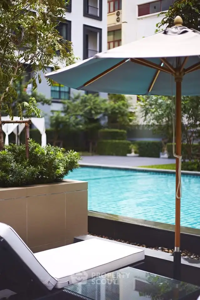 Luxurious poolside area with sun loungers and umbrellas in a modern residential complex.