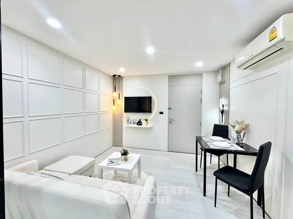 Modern living room with sleek white decor and dining area, featuring ambient lighting and air conditioning.