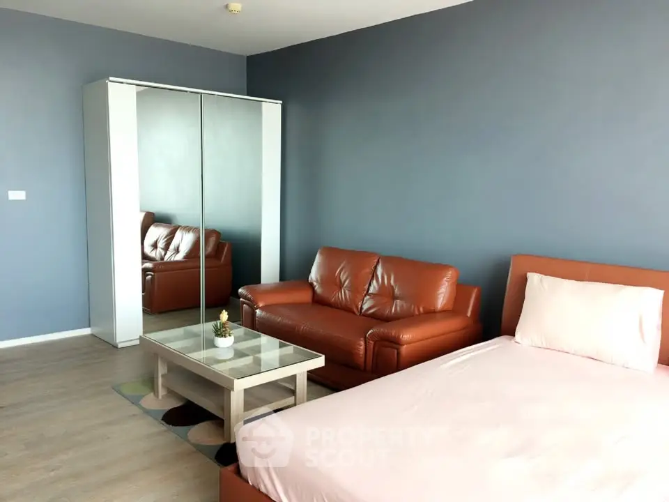 Modern studio apartment with sleek leather sofa and mirrored wardrobe