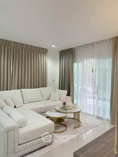 Elegant living room with white sectional sofa and chic decor, featuring floor-to-ceiling windows and luxurious curtains.