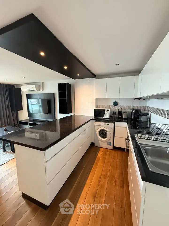 Modern kitchen with sleek design, featuring an island, washing machine, and open layout.