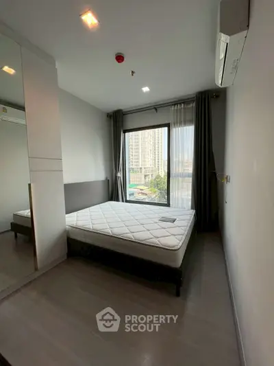 Modern bedroom with large window and city view, featuring sleek design and ample natural light.
