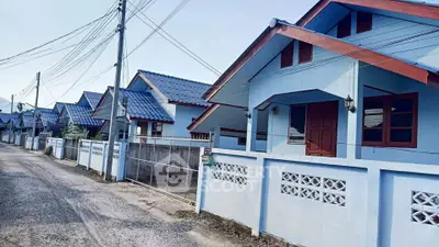 Charming row of blue houses with gabled roofs and fenced yards on a quiet street.