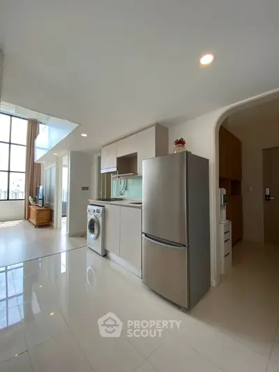 Modern open-layout kitchen with stainless steel appliances and spacious living area.
