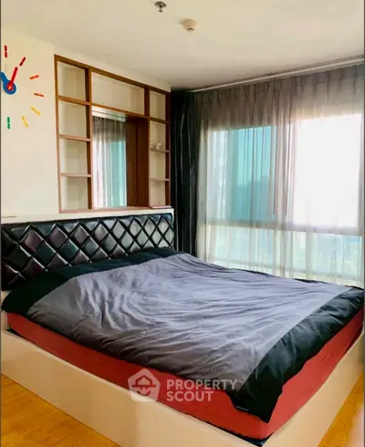 Spacious bedroom with large window and modern decor in a stylish apartment.