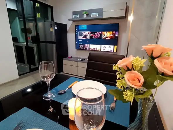Modern dining area with elegant table setting and wall-mounted TV in a stylish apartment.
