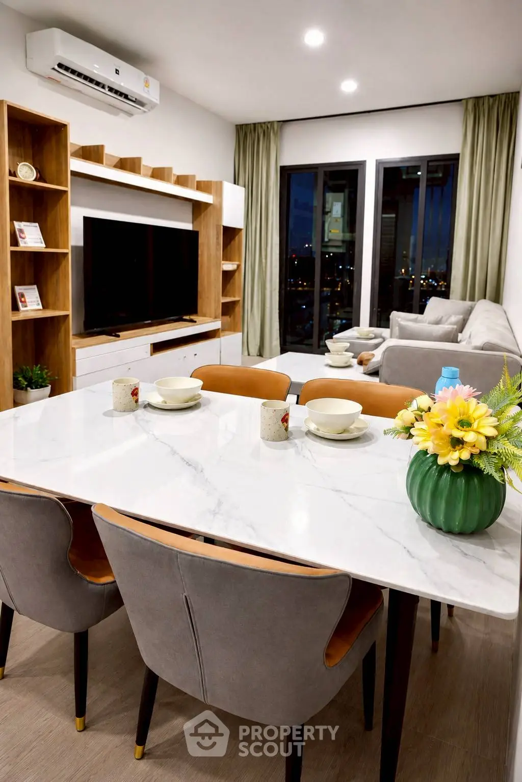 Modern living room with elegant dining area and city view, featuring stylish furniture and decor.