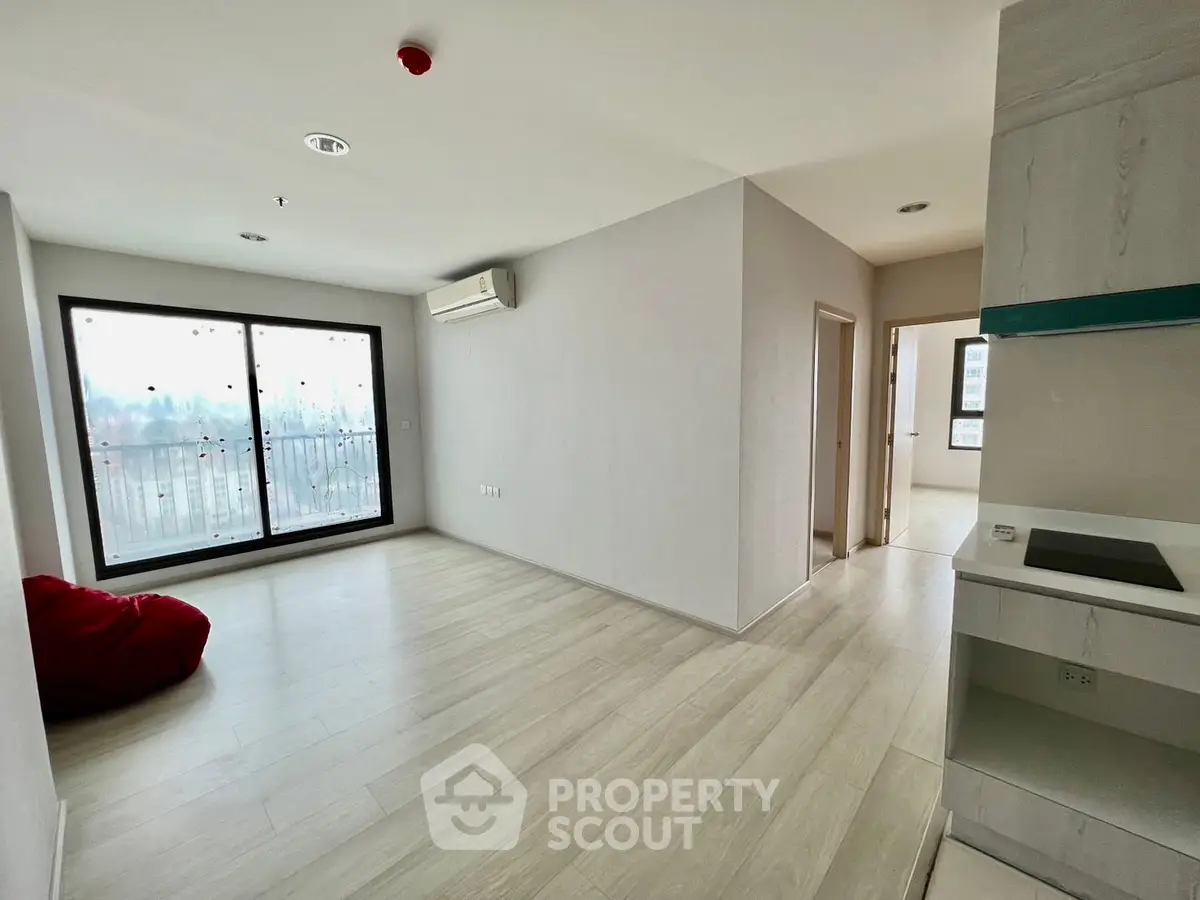 Spacious modern living room with large windows and sleek flooring in a contemporary apartment.