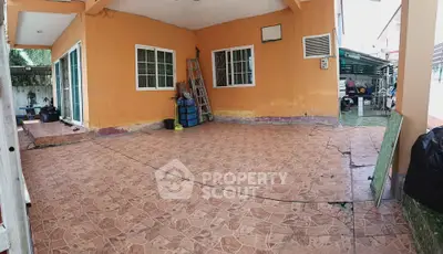 Spacious outdoor patio with tiled flooring and orange walls, perfect for gatherings and relaxation.