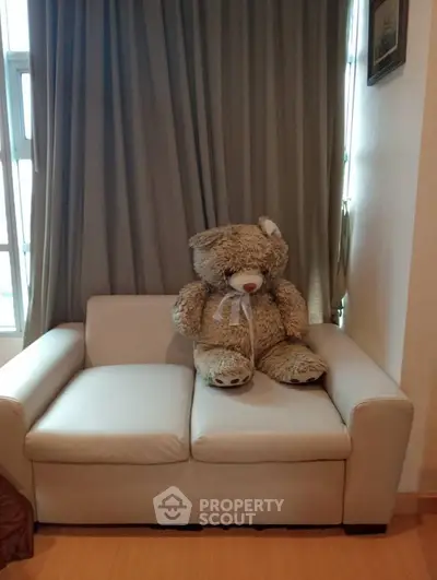 Cozy living room with plush teddy bear on a modern white sofa, perfect for relaxation.